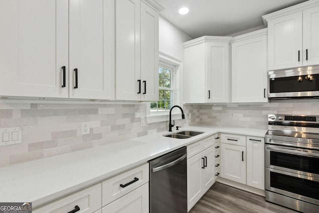 kitchen featuring a sink, dark wood-style floors, stainless steel appliances, white cabinets, and light countertops