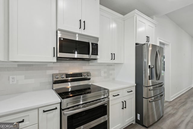 kitchen featuring light wood-type flooring, tasteful backsplash, white cabinetry, appliances with stainless steel finishes, and light countertops