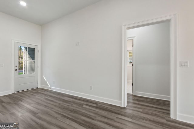 spare room with baseboards and dark wood-style flooring