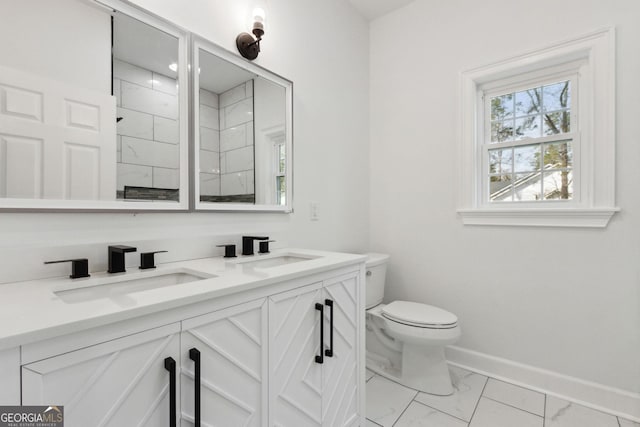 bathroom featuring baseboards, toilet, double vanity, marble finish floor, and a sink