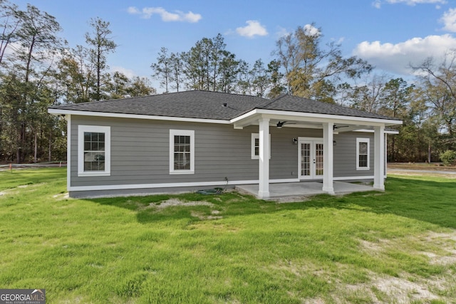 rear view of property featuring a ceiling fan, roof with shingles, french doors, a patio area, and a lawn