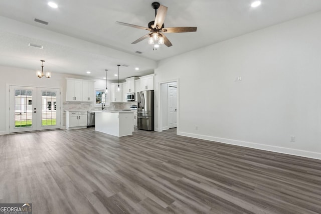 unfurnished living room with visible vents, dark wood-type flooring, ceiling fan with notable chandelier, french doors, and baseboards