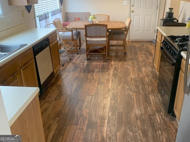 kitchen featuring dark wood-style flooring, brown cabinets, light countertops, black gas range oven, and white dishwasher