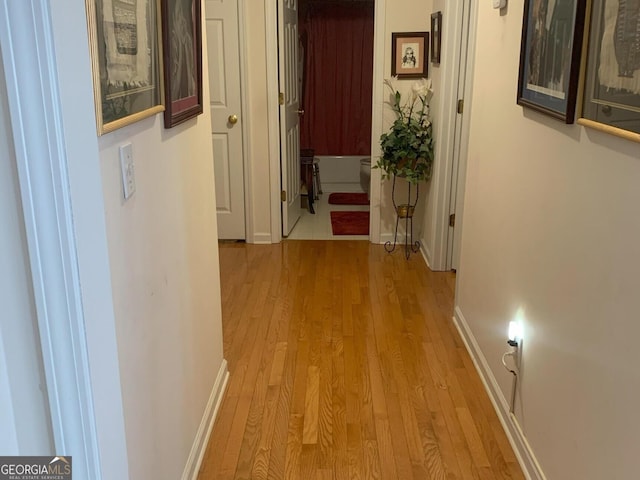 hall with baseboards and light wood finished floors