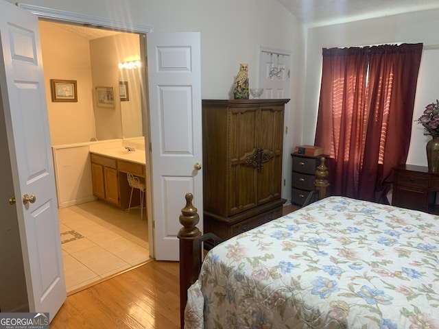 bedroom featuring vaulted ceiling, a sink, and light wood-style flooring