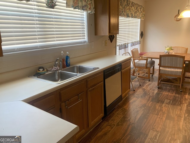 kitchen featuring dishwashing machine, a sink, light countertops, backsplash, and dark wood finished floors