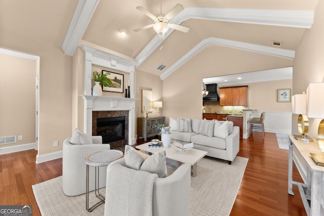 living room with lofted ceiling, visible vents, wood finished floors, and a high end fireplace