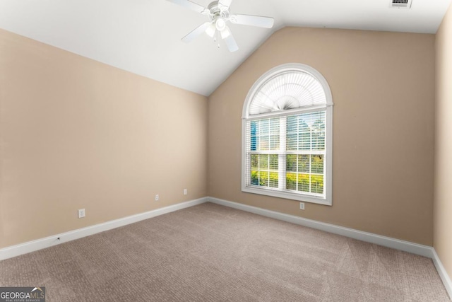 spare room with lofted ceiling, carpet flooring, a ceiling fan, visible vents, and baseboards