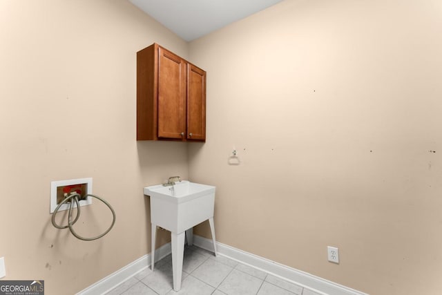 washroom with light tile patterned floors, hookup for a washing machine, cabinet space, and baseboards