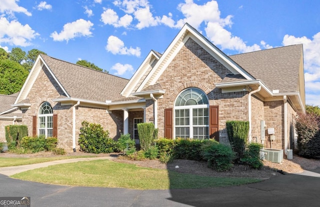 view of front of house with brick siding and roof with shingles