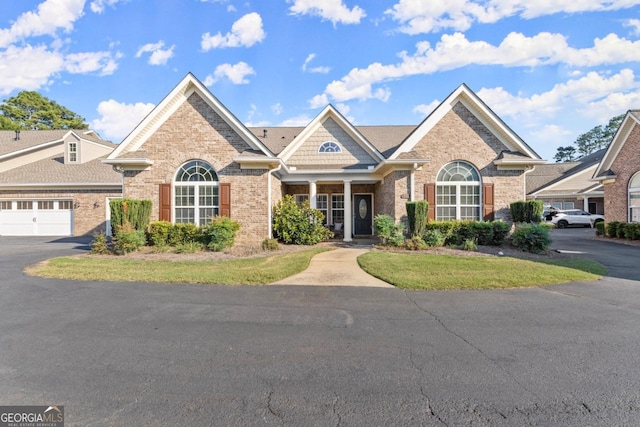 view of front of home featuring brick siding, an attached garage, and aphalt driveway