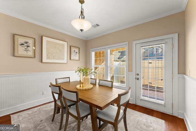 dining space featuring ornamental molding, wainscoting, wood finished floors, and visible vents