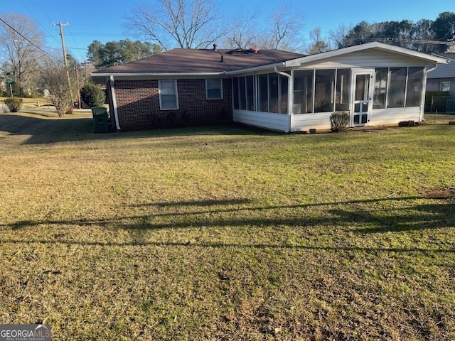 rear view of house with a sunroom, a lawn, and brick siding