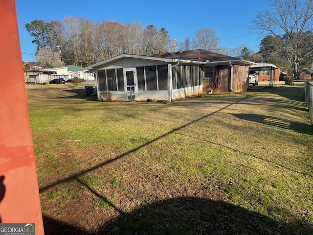 back of house featuring a yard, brick siding, and a sunroom