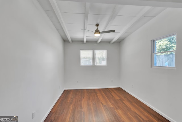 empty room with dark wood-style floors, beam ceiling, plenty of natural light, and baseboards