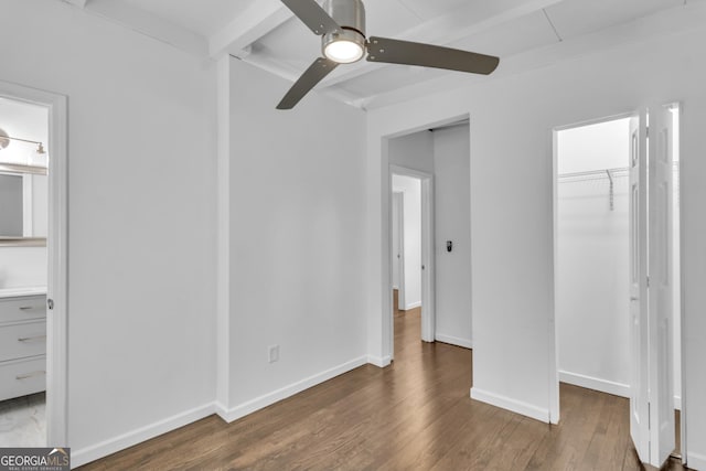 unfurnished bedroom with baseboards, ceiling fan, beamed ceiling, wood finished floors, and a closet