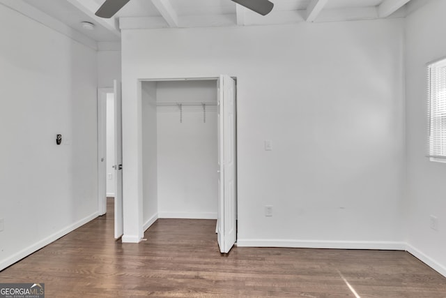 unfurnished bedroom featuring a closet, beamed ceiling, wood finished floors, and baseboards