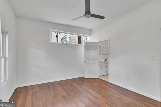 unfurnished bedroom featuring ensuite bathroom, ceiling fan, wood finished floors, and baseboards