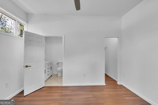 unfurnished bedroom featuring baseboards, wood finished floors, and ensuite bathroom