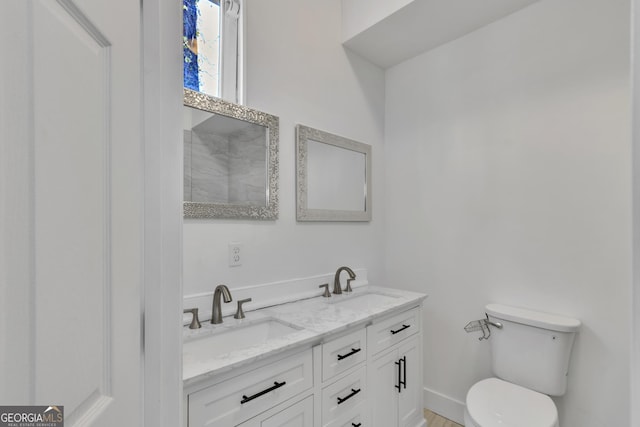 bathroom featuring baseboards, a sink, toilet, and double vanity