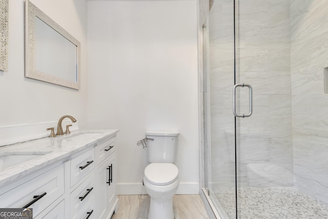 bathroom with double vanity, toilet, a stall shower, a sink, and baseboards