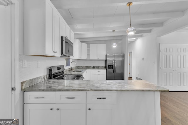 kitchen with appliances with stainless steel finishes, a peninsula, light stone countertops, a sink, and beam ceiling