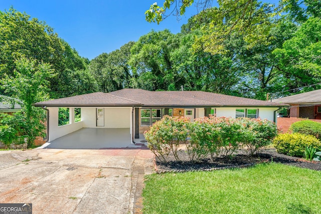 ranch-style home with driveway, a shingled roof, stucco siding, an attached carport, and a front yard