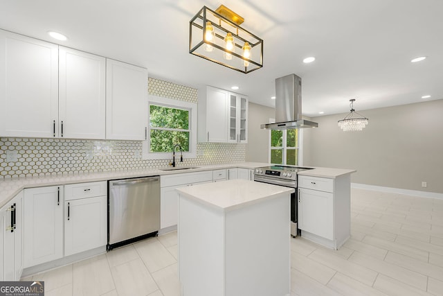 kitchen with stainless steel appliances, tasteful backsplash, a sink, island range hood, and a peninsula