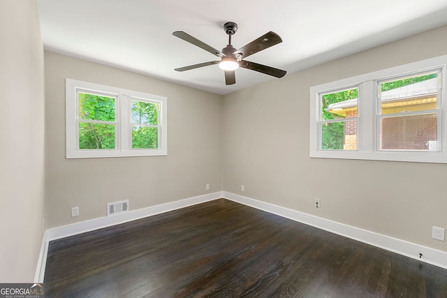 unfurnished room with dark wood-type flooring, visible vents, baseboards, and a ceiling fan