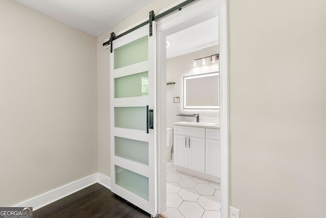2682 Miriam Ln, Decatur, GA 30032 - hallway featuring a barn door, a sink, baseboards, and wood finished floors