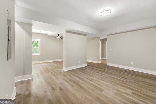 below grade area with light wood-style floors, baseboards, and a ceiling fan