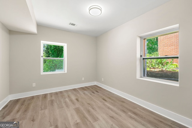 spare room featuring light wood-type flooring, visible vents, and baseboards