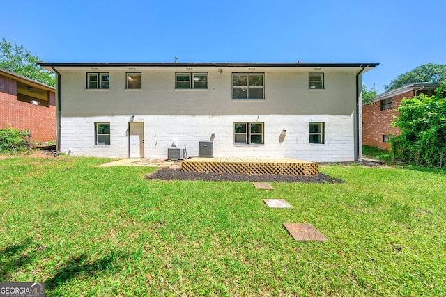 back of property with brick siding, central AC unit, and a yard