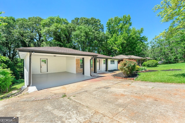 view of front facade featuring an attached carport, driveway, and a front lawn