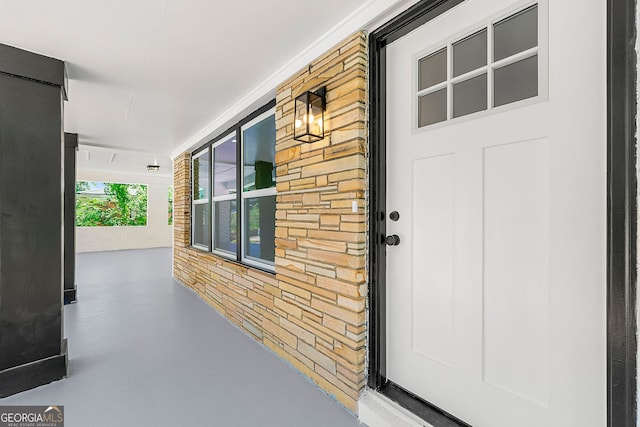 view of exterior entry featuring a porch and brick siding