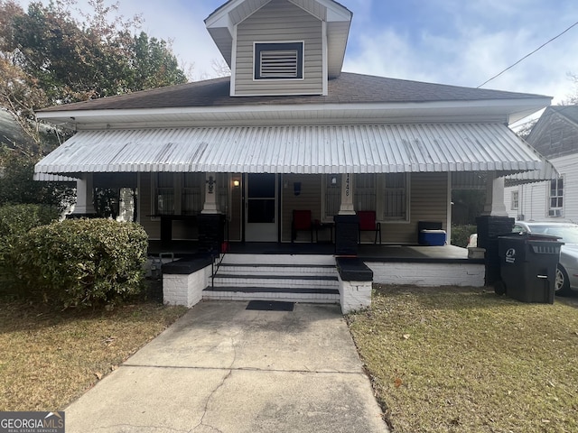 view of front facade featuring a front lawn, a porch, and roof with shingles