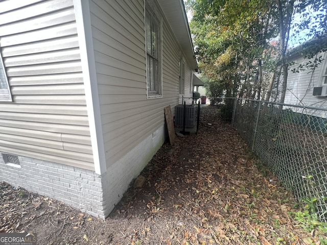 view of side of home with crawl space, cooling unit, and a fenced backyard