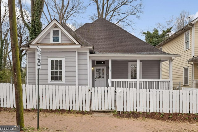 view of front of home with covered porch, a fenced front yard, a gate, and roof with shingles