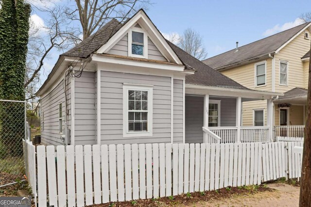 view of front of home featuring covered porch, roof with shingles, and fence