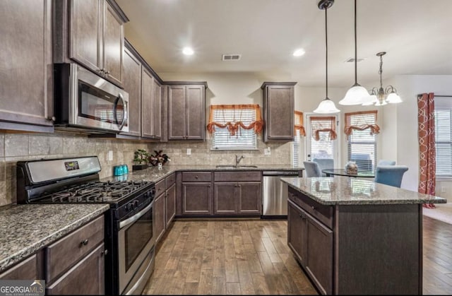 kitchen with dark brown cabinetry, stainless steel appliances, visible vents, decorative backsplash, and dark wood-style floors