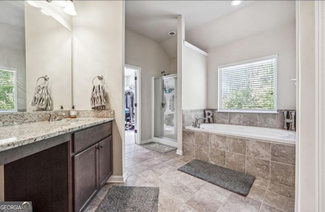 bathroom with a garden tub, lofted ceiling, a spacious closet, a shower stall, and vanity