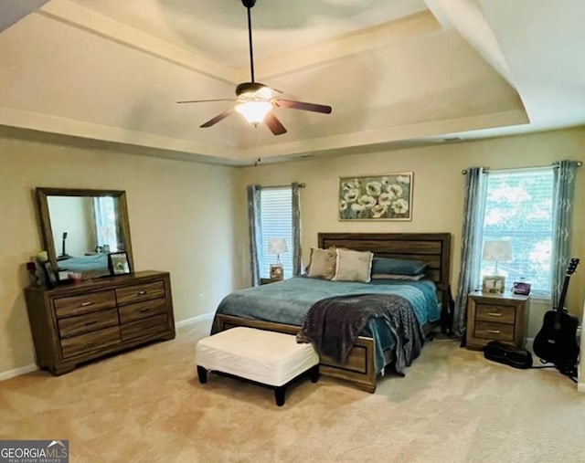 bedroom featuring carpet, a raised ceiling, and baseboards