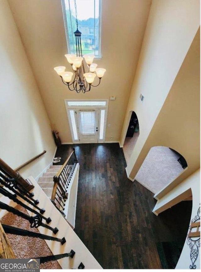 entryway with a chandelier, a high ceiling, stairway, and wood finished floors