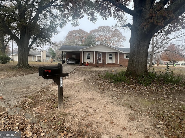 view of front of house with dirt driveway, an attached carport, and brick siding