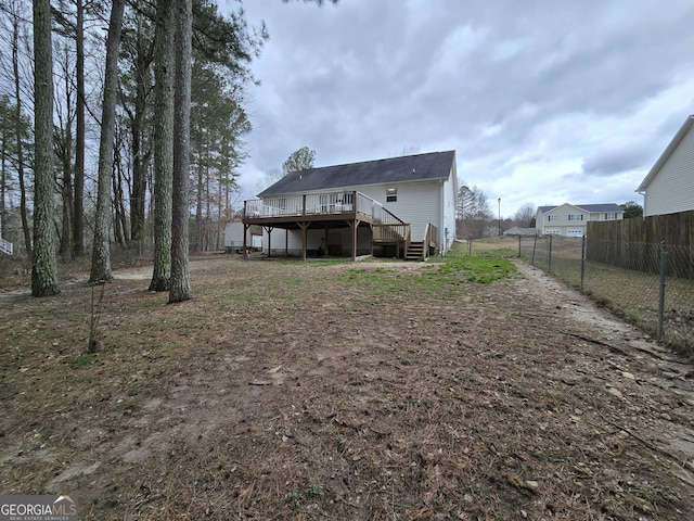 rear view of property featuring a deck, fence, and stairs