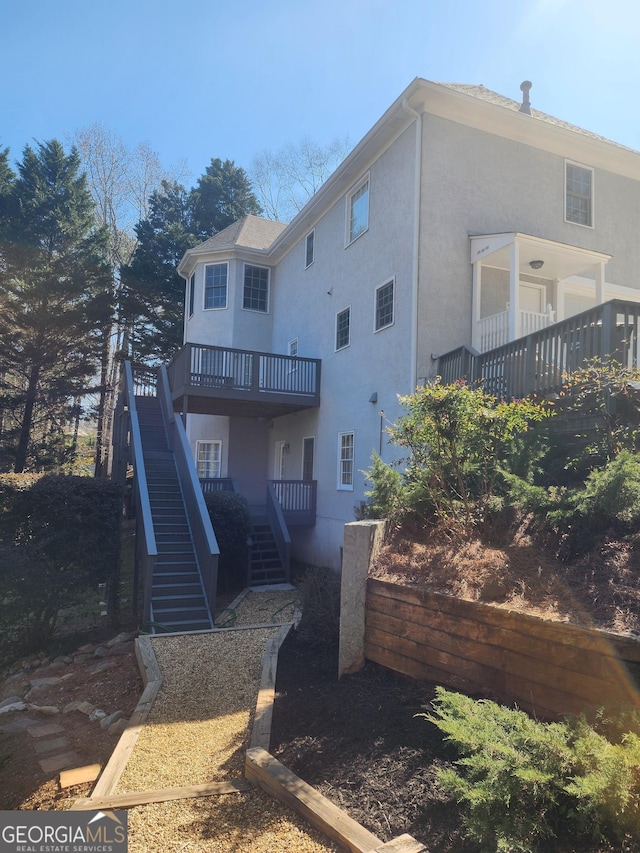 rear view of property with stairway and stucco siding