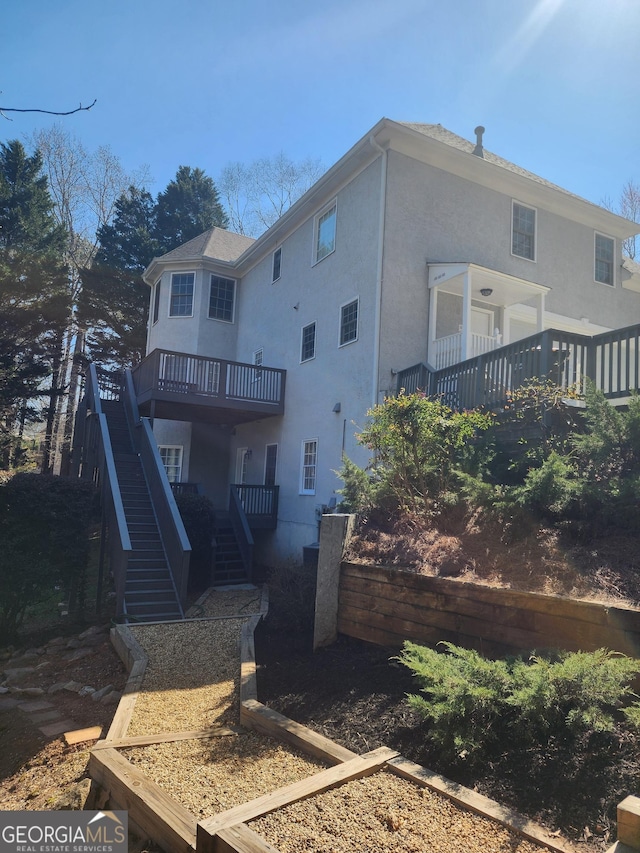 rear view of house with stairway and stucco siding