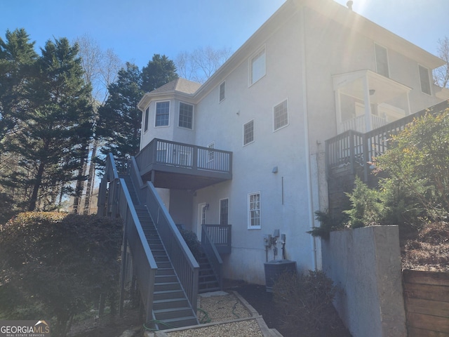 rear view of property featuring stairs, central AC, and stucco siding