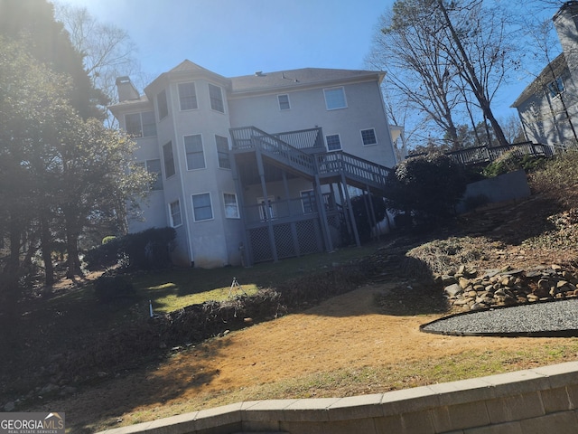 rear view of property featuring stairway, a deck, and stucco siding