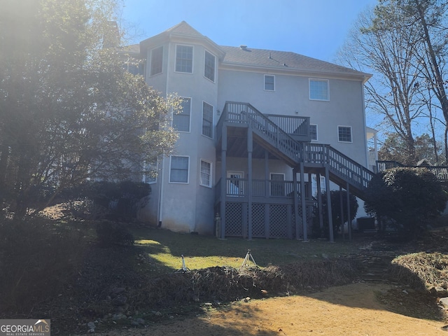 rear view of house featuring a yard, stairway, and stucco siding